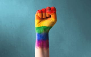 An image of a clenched fist painted in rainbow colors, representing the fight for LGBTQIA inclusion