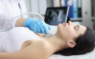 A woman getting an ultrasound on her throat is pictured.
