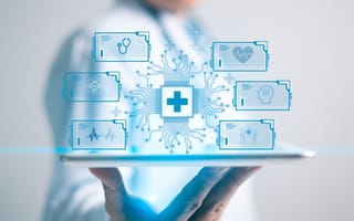 A person holds a tablet displaying digital medical icons, including stethoscope, heart, and brain, connected by circuitry lines.