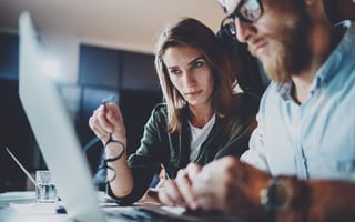 Business professionals look at a computer together.