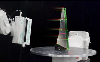 A robotic arm with an "Augmentus" device scans a metal object with green and red markers, showcasing precision in technological analysis.