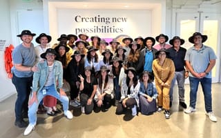 A group photo of the Udemy team wearing matching wide brimmed hats.