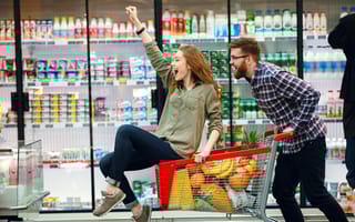oung happy man pushing shopping cart with his girfriend inside