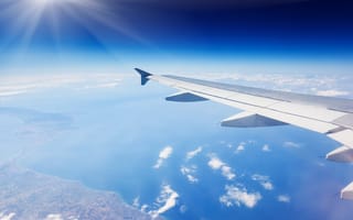 An aircraft wing is shown flying over earth.