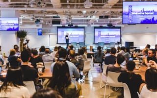 Large group of employees watching a presentation and enjoying refreshments at Coinbase company office