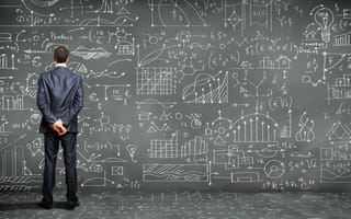 A man stands in front of a wall covered in scientific and mathematical equations.