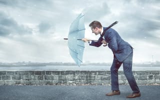 A tech employee staying resilient pushing against the wind in the rain.
