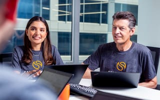 Two employees at Smokeball sit at a conference table with laptops in front of them