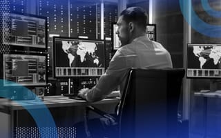 A cybersecurity professional works on multiple monitors