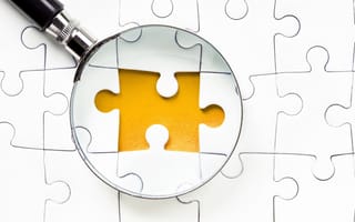 Image of a magnifying glass over one missing piece in an otherwise completed puzzle.