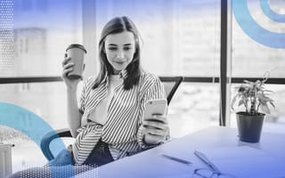 A woman checks email on her phone with a cup of coffee