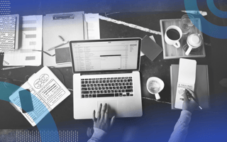 sales prospect email woman's hands scrolling on laptop and taking notes with notebooks, papers, and coffee on the desk
