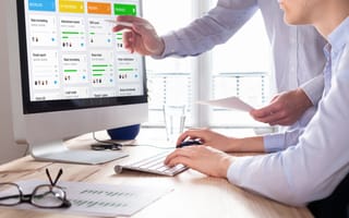 Manager points at computer screen as staff member types