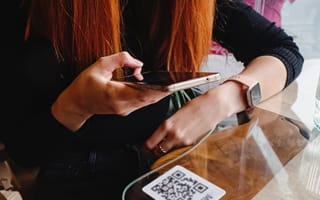 Woman scanning a QR code in a restaurant.