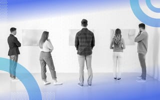 Several people regard canvases at an art gallery.