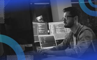 A computer programmer works with code on multiple monitors