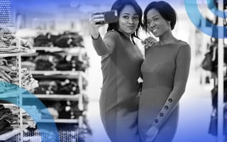 Two shoppers pose in matching dresses while using a phone.