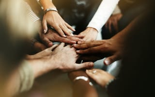 A group of employee hands come together in camaraderie.