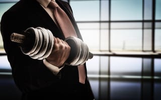 A man in a business suit lifting weights for muscle development.