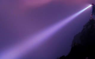 A person job searching through thick fog with a flashlight.