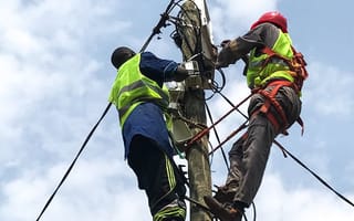 SparkMeter workers install the company's grid visibility platform to an electricity pole.