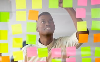 A tech employee’s face peeks through a wall covered in Post-it Notes