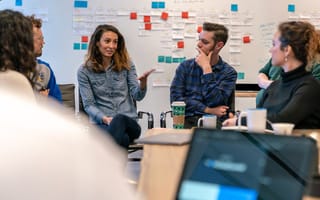 Ontra coworkers having a team meeting in the office with post it notes on the wall in the background