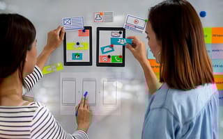 Two designes holding up user journey pictures.