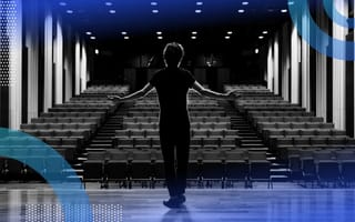 A performer stands onstage in front of an empty theatre