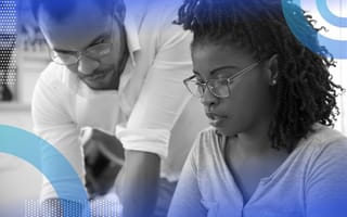 A Black man leans over the shoulder of a younger Black woman, showing her something. /women-tech/male-allies-mentor-women