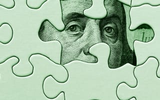 A puzzle with a piece removed to reveal Benjamin Franklin's face from the 100 dollar bill.