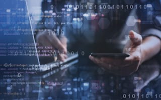 An engineer consults their phone and laptop.