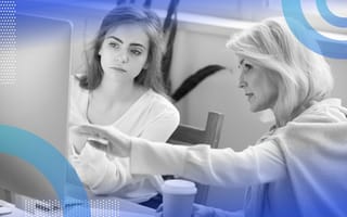 An older woman points something out on a computer screen to a younger woman.