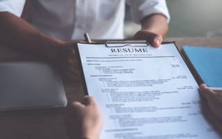 a recent college grad is handing a resume to an interviewer