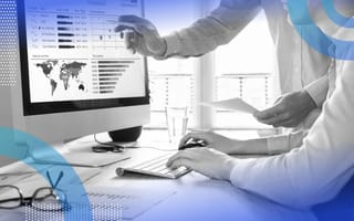 Two people look at analytics and charts on a monitor