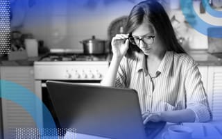 A woman looks at a laptop and adjusts her glasses