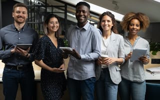 A group of professionals smiling and holding tablets and other devices used to support professional development programs