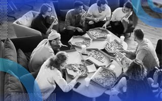 A group of people gather around a table covered with different pizzas. /remote-work/make-remote-work-more-fun