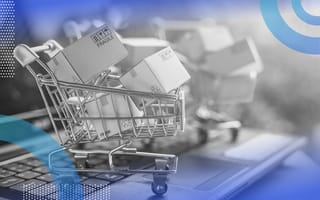 A small shopping cart filled with packages atop a laptop