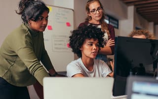 Software developers looking at a monitor discussing source code