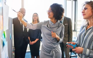group of focused businesspeople brainstorming together on a whiteboard during a strategy session in a bright modern office