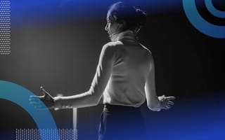 A female conference speaker faces the crowd with arms outstretched. https://builtin.com/artificial-intelligence