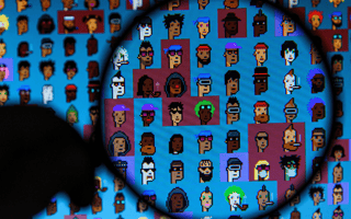A person holding a magnifying glass to a screen filled with cryptopunks.