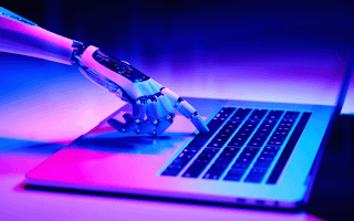 A robot are pressing the space bar on a laptop computer as a part of their robotic process automation.