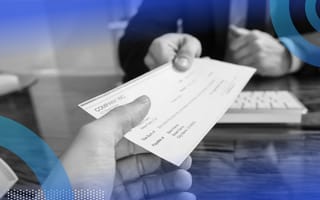 A person hands a check to another across a desk
