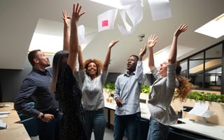Diverse group of coworkers throwing papers in the air to celebrate