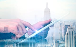 Side view of hand using tablet on New York City background.