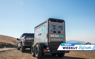 A truck pulling a trailer both with Moxion's logo on them.