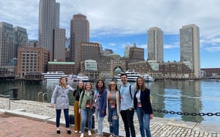 a group of seven people standing in front of Boston's harbor