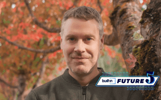 Tom Lapham, CEO of CHEQ, poses for a photo outside by a tree with changing leaves